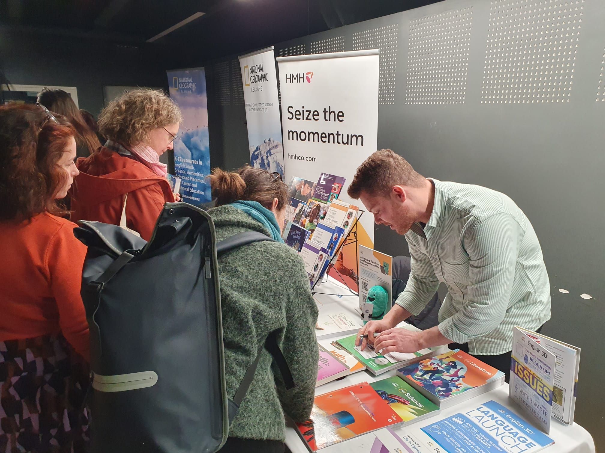 An exhibitor displaying pamphlets about their service while speaking to participants at ELSA TDD